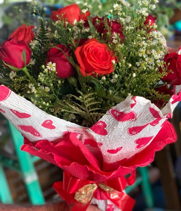 rosas vermelhas folhagens e astromelhas , decoradas com papel crepom e  laço de fitas.