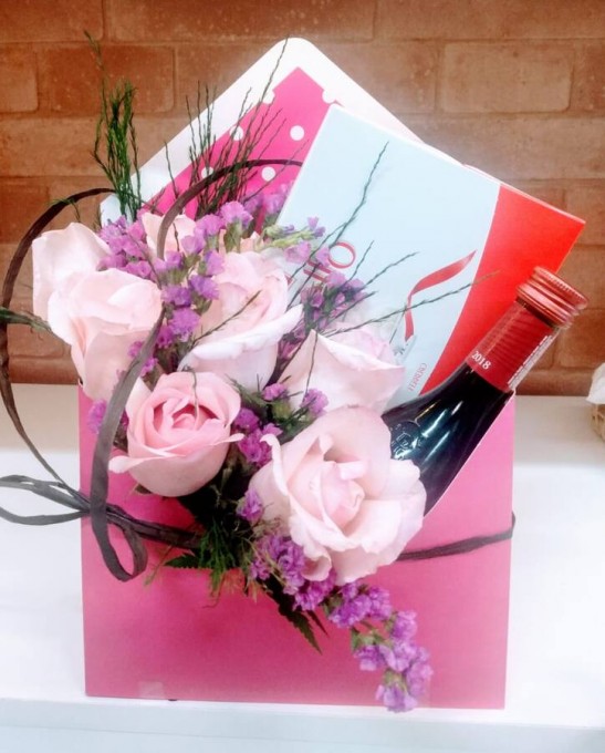 Envelope cartonado com lindo arranjo de flores variadas, chocolate Raffaello e vinho tinto suave.