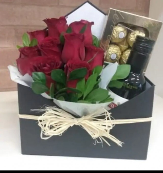 Envelope cartonado com arranjo de rosas vermelhas, acompanhadas de um chocolate Ferrero Roche e um vinho.